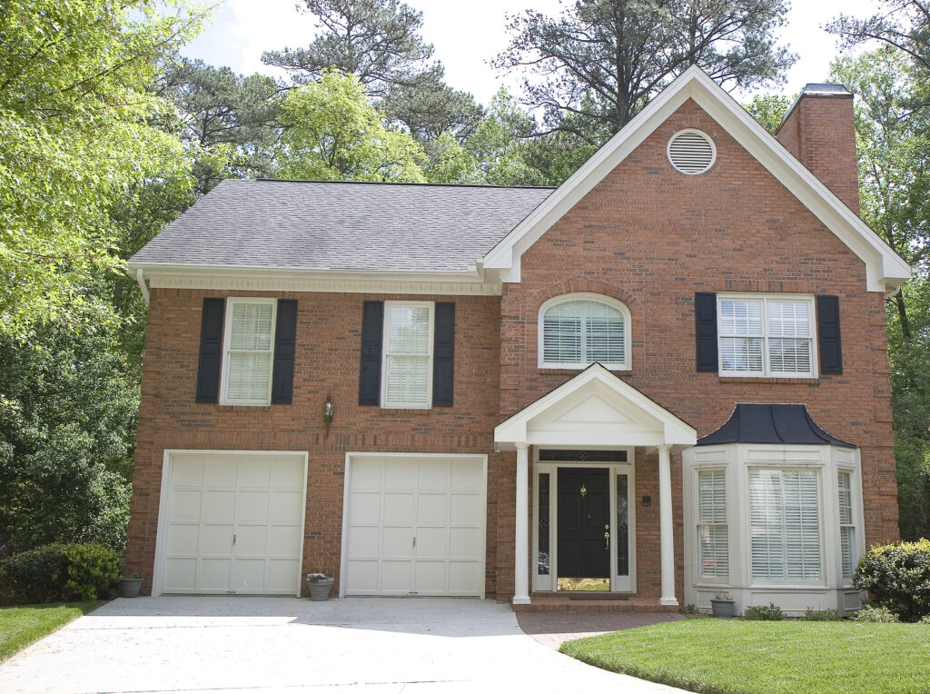 A nice brick house with a round attic vent installed by a roofer in AThens, TX.